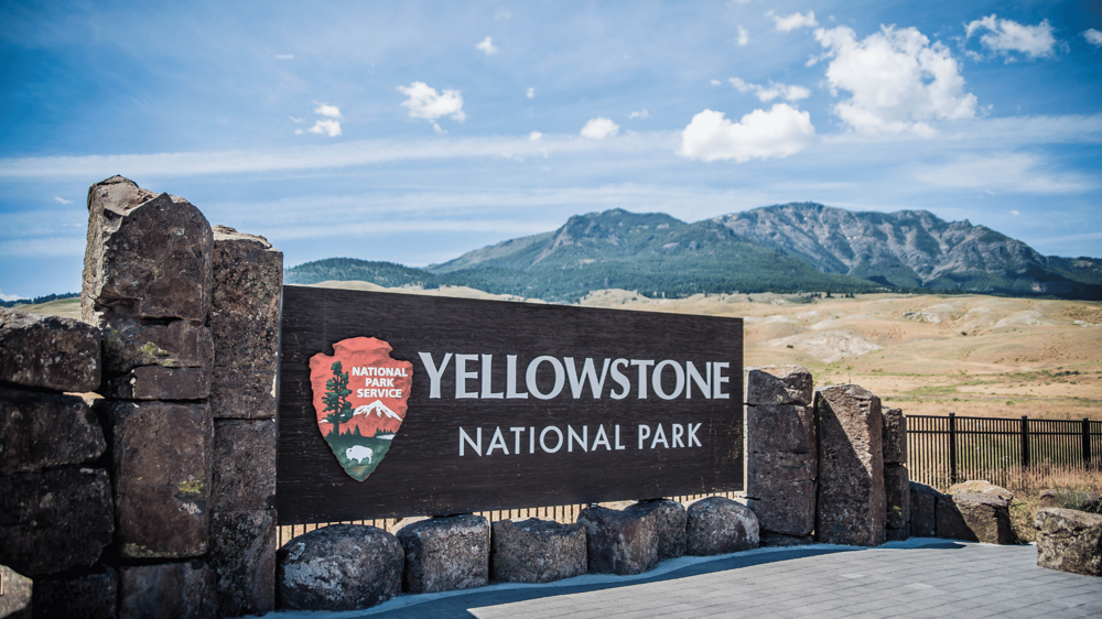 yellowstone nemzeti park tábla hegyekkel a háttérben