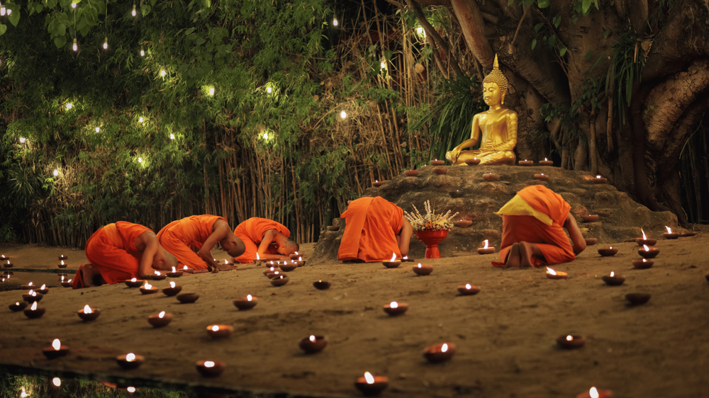 Makha Bucha Fesztiválről egy kép, ahol a Buddhisták egy fa előtt imádkoznak