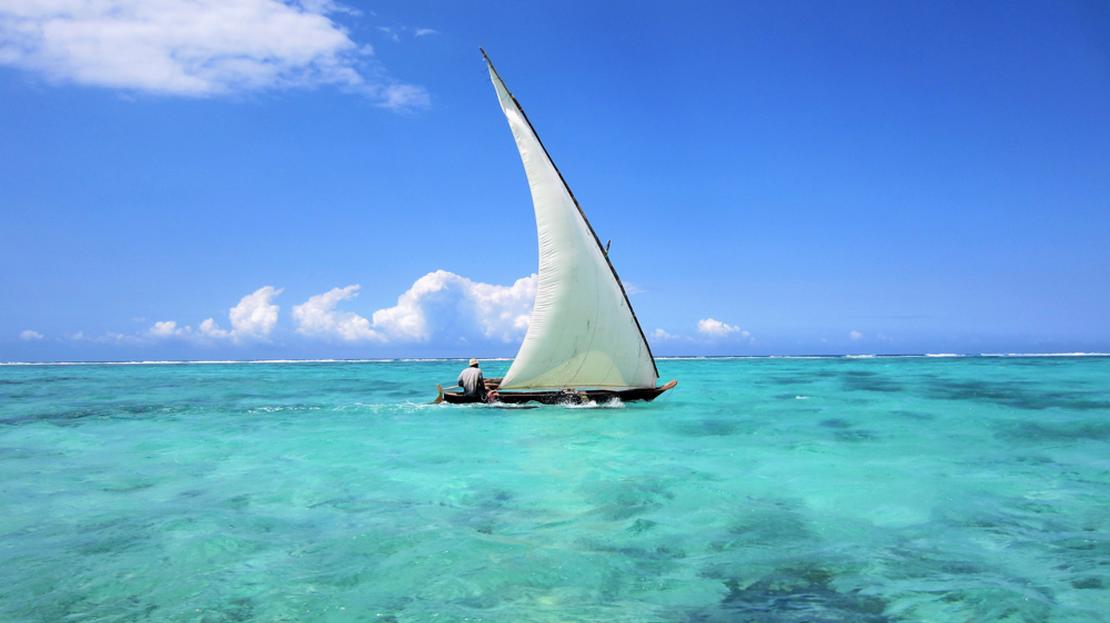 Egy zanzibári lakos ül egy vitorlás csónakban és utazik a vízen