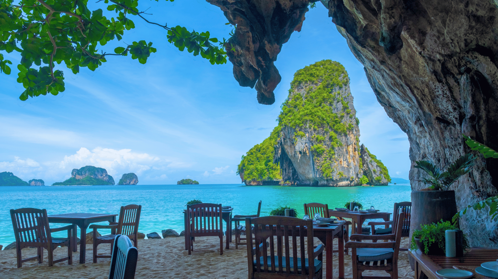 Railay Strand, ahol a parton székeken ülve látjuk az óriási vízből kiemelkedő sziklákat